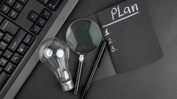 top-view-plan-written-black-notepad-lupa-keyboard-light-bulb-pen-black-table img